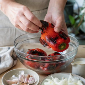 Upečené papriky, cibuľa a cesnak v nádobe pripravené na rozmixovanie.