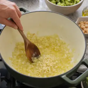 Cibuľa a cesnak sa opekajú na olivovom oleji vo väčšom hrnci.