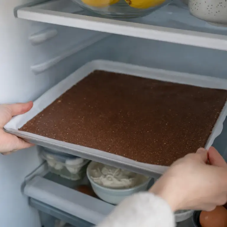 Rozkrojená roláda s tmavším sušienkovým plátom a svetlým krémom.